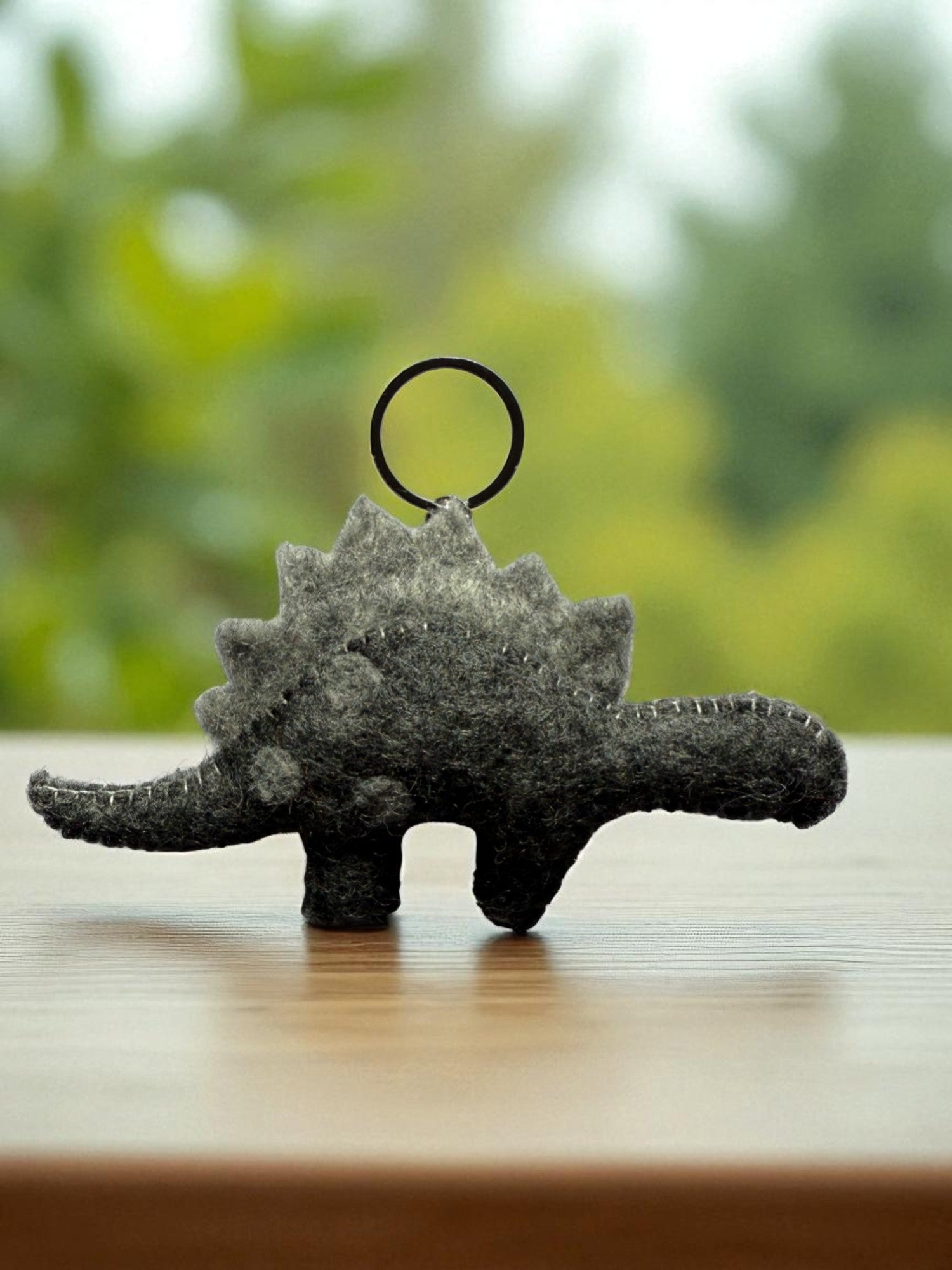 Handmade felt keychain featuring a gray dinosaur by artisans in Nepal, fair trade and eco-friendly