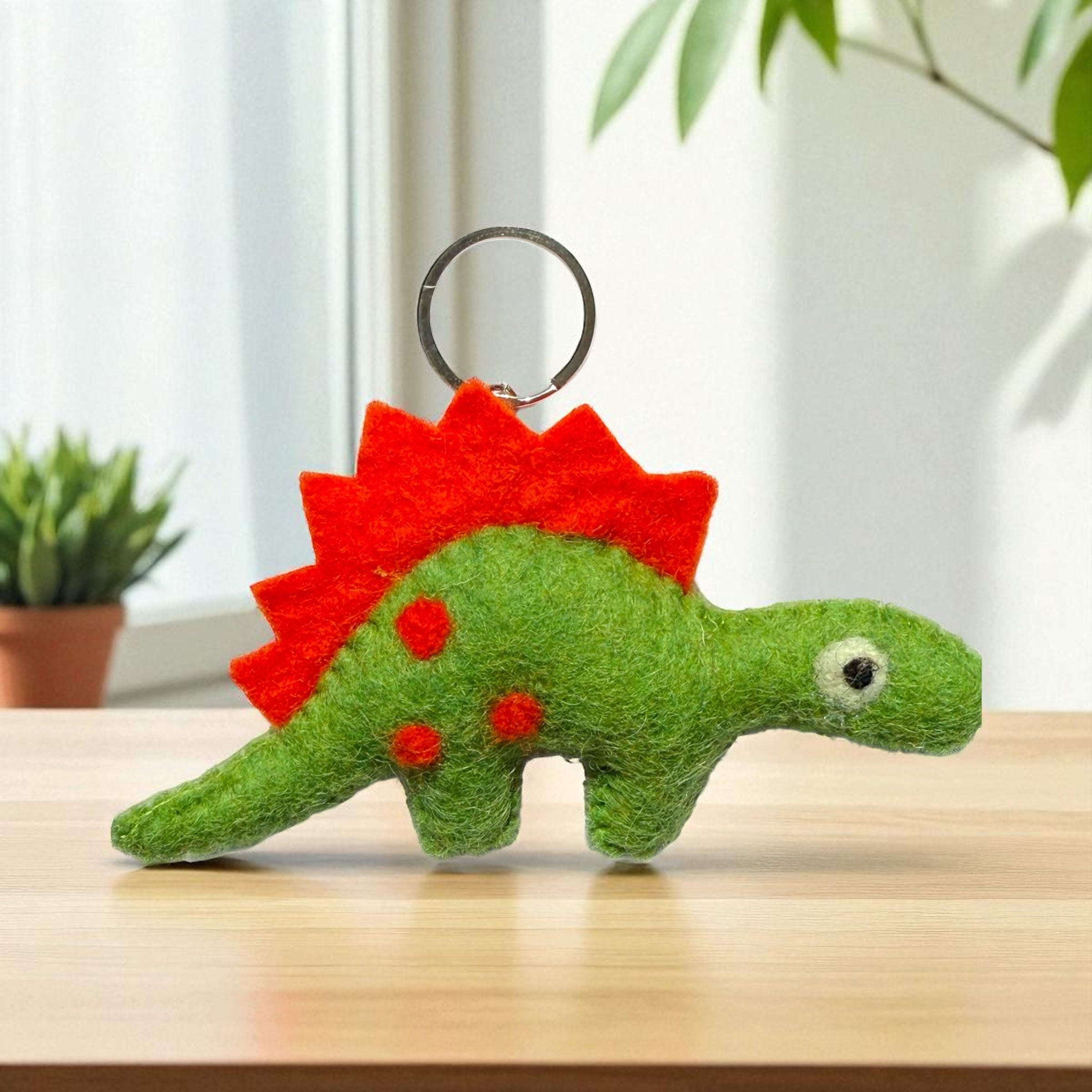 Handmade felt keychain featuring a green dinosaur crafted by artisans in Nepal, fair trade and eco-friendly