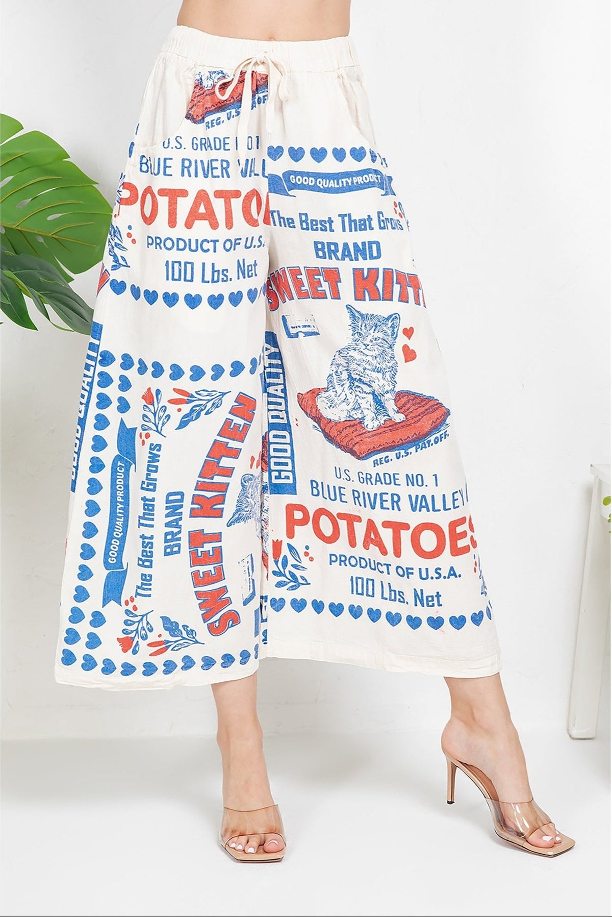 Vintage-inspired wide-leg pants with Sweet Kitten and Blue River Valley potato sack print, 100% cotton high-waisted trousers with retro red and blue typography graphics