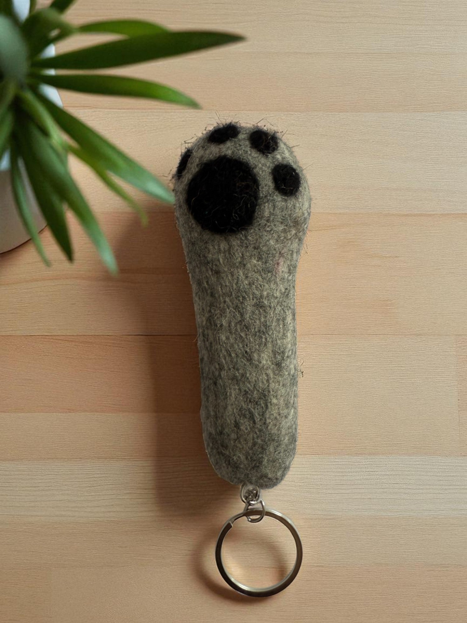 Handmade felt keychain featuring a gray paw by artisans in Nepal, fair trade and eco-friendly