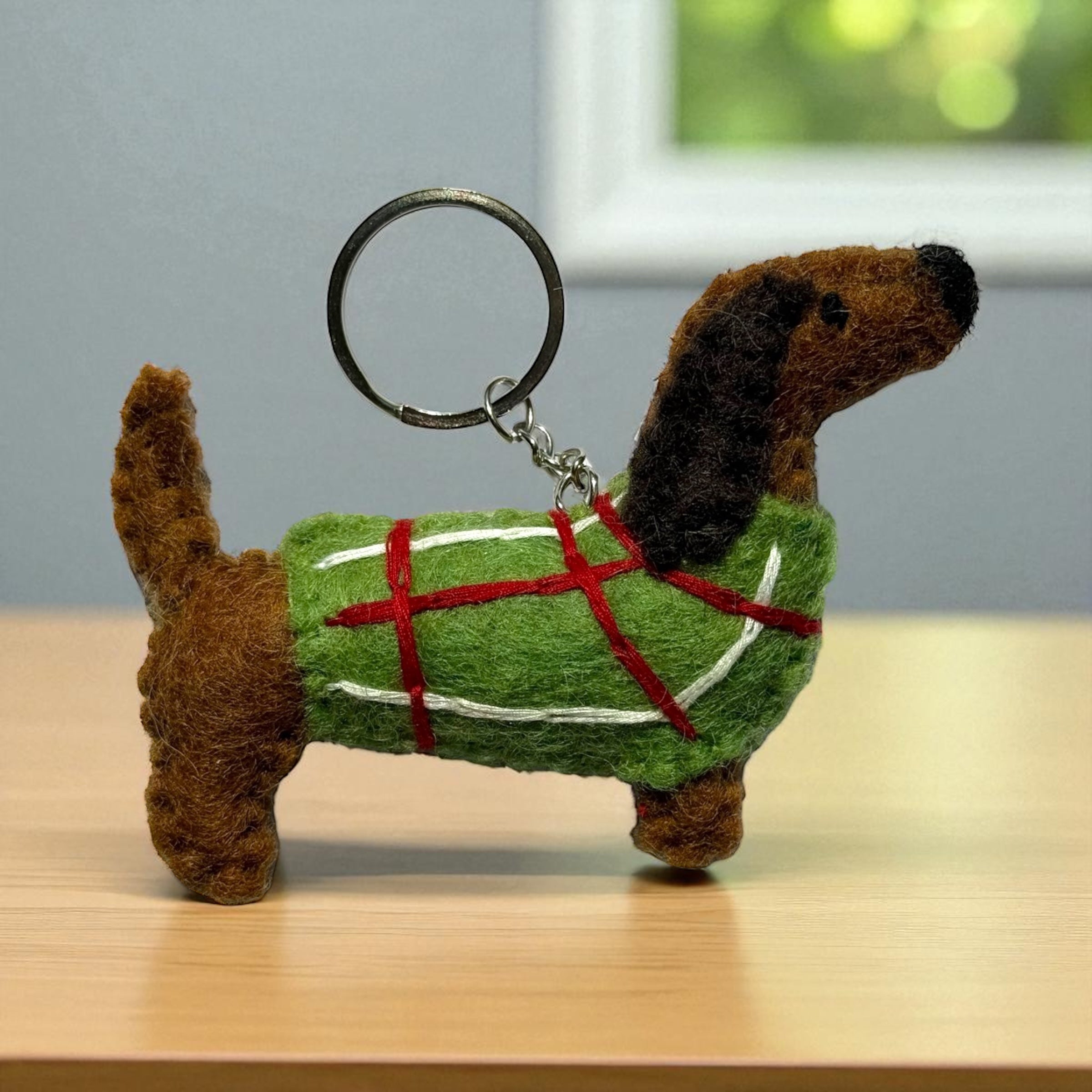 Handmade felt keychain featuring a dachshund wearing a green sweater crafted by artisans in Nepal, fair trade and eco-friendly