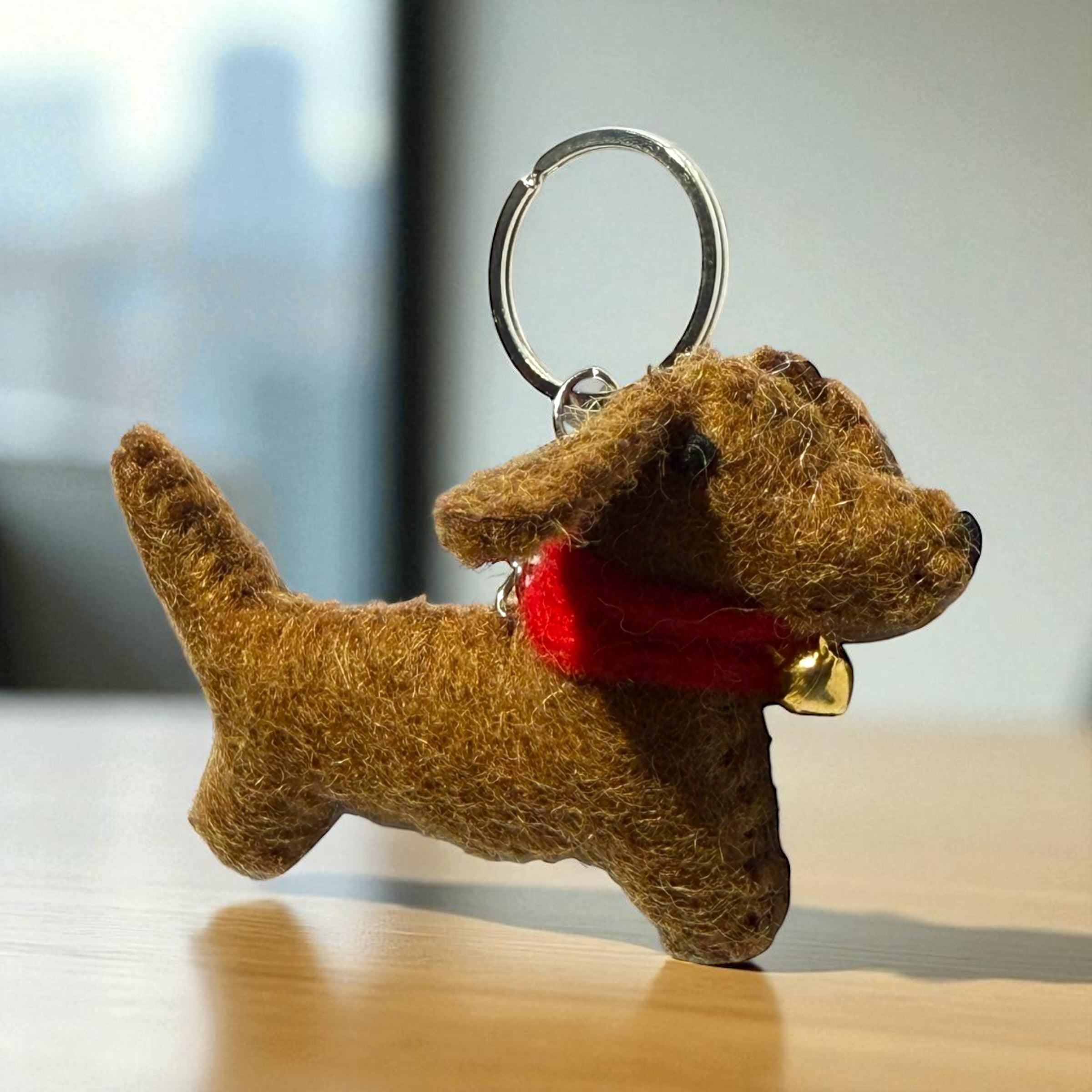 Handmade felt keychain featuring a brown dachshund with a red bell crafted by artisans in Nepal, fair trade and eco-friendly