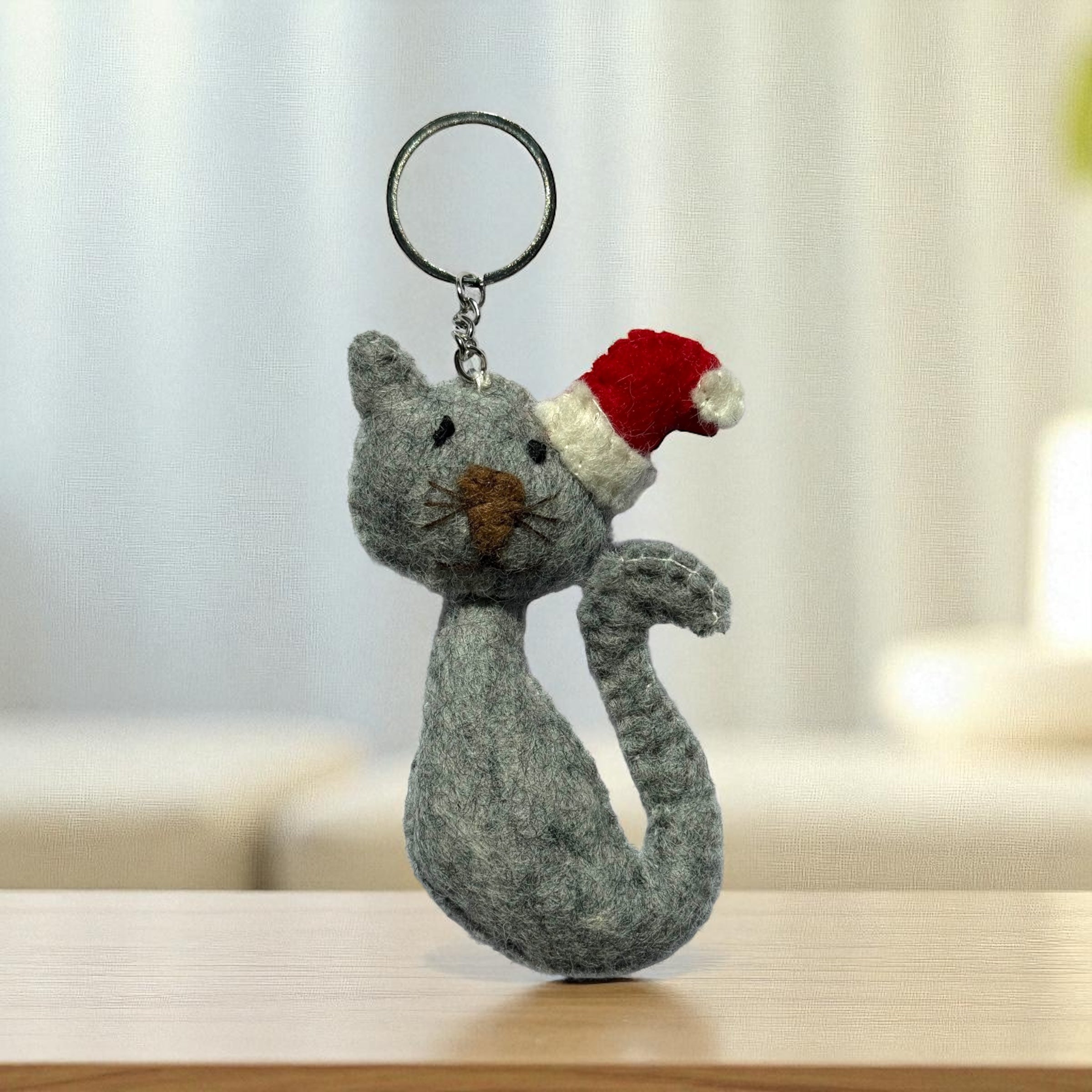 Handmade felt keychain featuring a gray cat wearing santa hat crafted by artisans in Nepal, fair trade and eco-friendly