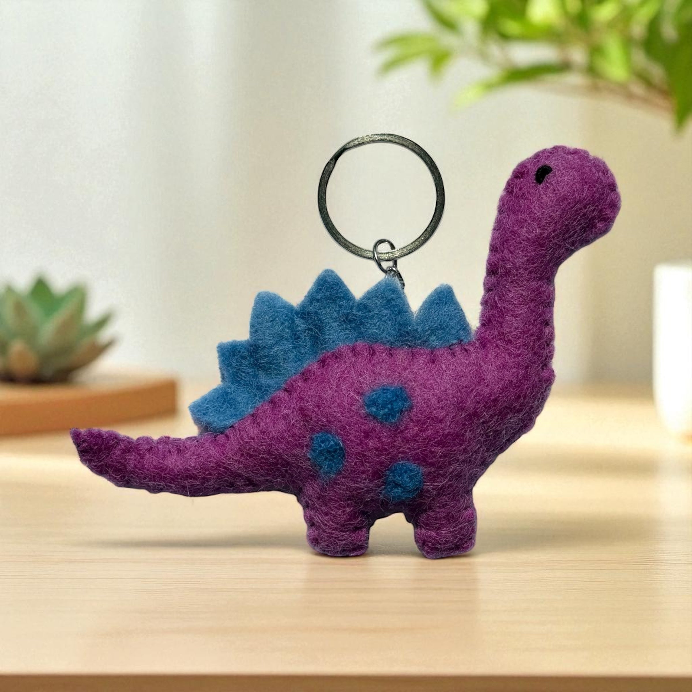 Handmade felt keychain featuring a purple dinosaur crafted by artisans in Nepal, fair trade and eco-friendly
