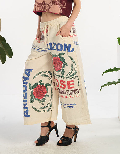 Person wearing cream-colored pants with rose and arizona rose feedsack design, standing against a white background.