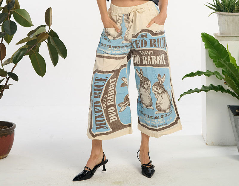 Woman wearing a rabbit printed wide-leg pants standing in a room with plants.