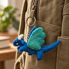 Handmade felt Blue Dragon keychain displayed on a bag