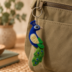 Handmade felt Peacock keychain displayed on a bag