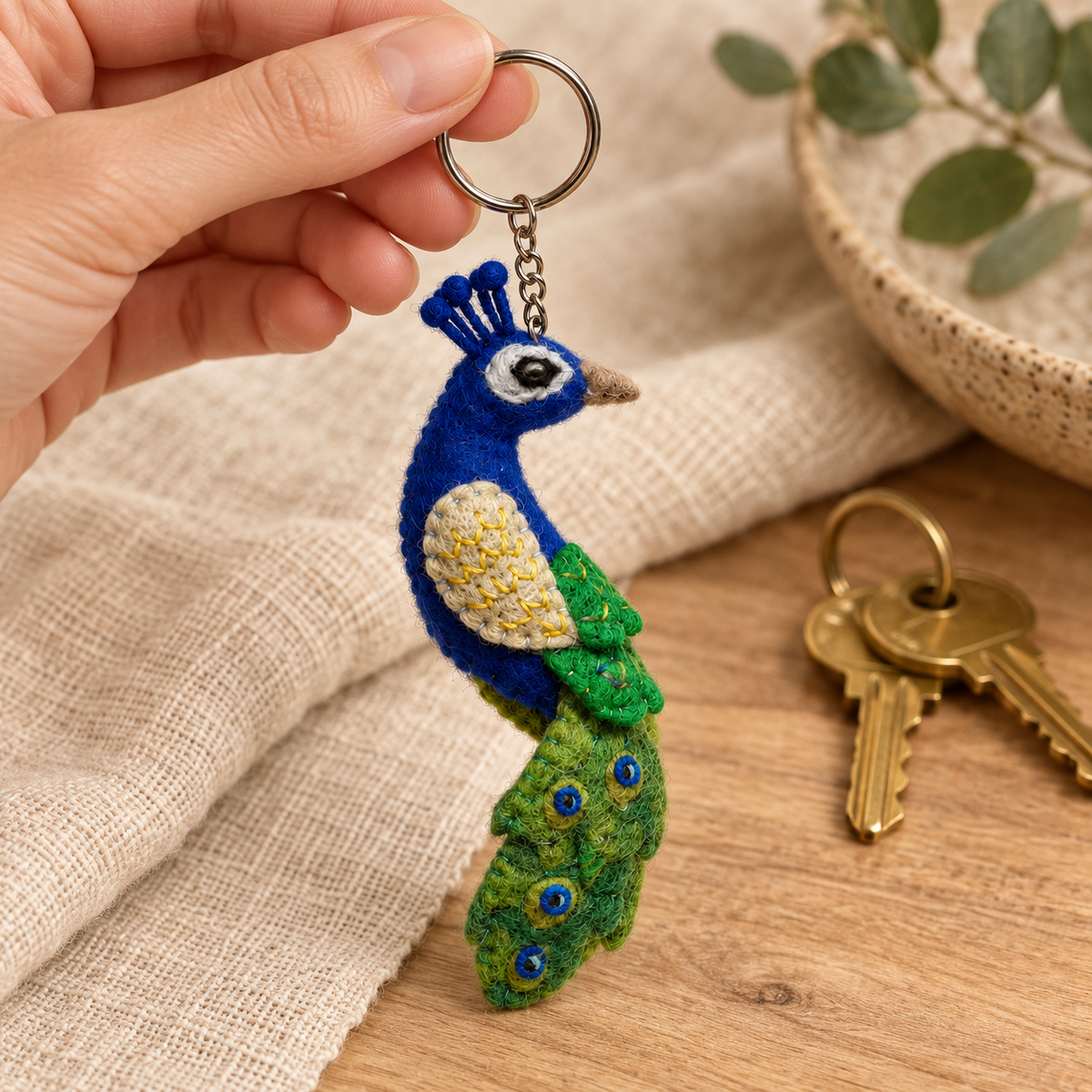 Handmade felt Peacock keychain shown in a lifestyle setting