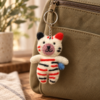 Handmade felt Striped Paw White keychain displayed on a bag