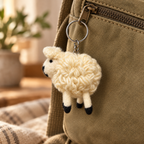 Handmade felt White Sheep keychain displayed on a bag